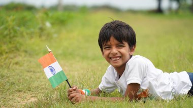 Beyaz ırktan yakışıklı küçük bir Hintli çocuk ya da çocuk Hindistan ulusal bayrağından ayakta duran ve vatanseverlik gösteren bir bebek giyer. Har Ghar Tiranga