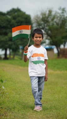 Beyaz ırktan yakışıklı küçük bir Hintli çocuk ya da çocuk Hindistan ulusal bayrağından ayakta duran ve vatanseverlik gösteren bir bebek giyer. Har Ghar Tiranga
