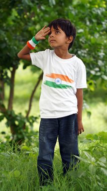 Üç renkli Hint tişörtü giyen, yüzü üç renkli boyayla boyanmış ve selam veren küçük bir çocuk. Bağımsızlık Günü ya da Cumhuriyet Günü 'nü kutluyoruz. Har Ghar Tiranga