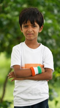 Beyaz ırktan yakışıklı küçük bir Hintli çocuk ya da çocuk Hindistan ulusal bayrağından ayakta duran ve vatanseverlik gösteren bir bebek giyer. Har Ghar Tiranga