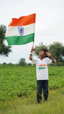 Üç renkli Hint tişörtü giyen, yüzü üç renkli boyayla boyanmış ve selam veren küçük bir çocuk. Bağımsızlık Günü ya da Cumhuriyet Günü 'nü kutluyoruz. Har Ghar Tiranga