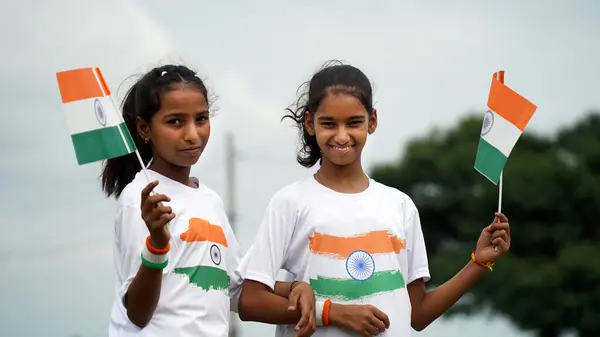 stock image Cute Indian girl holding Indian flag in her hand and smiling. Celebrating Independence day or Republic day in India. A girl showing pride of Tiranga. Har Ghar Tiranga