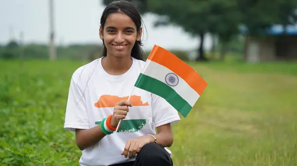 stock image Cute Indian girl holding Indian flag in her hand and smiling. Celebrating Independence day or Republic day in India. A girl showing pride of Tiranga. Har Ghar Tiranga