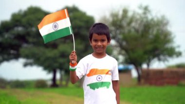 Sevimli küçük yerli köylü çocuk gururla üç renkli Hint bayrağını taşıyor. Ulusal bayrak taşıyan genç.