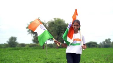 Elinde Kızılderili bayrağı tutan ve gülümseyen sevimli bir Hintli kız. Hindistan 'da Bağımsızlık Günü veya Cumhuriyet Günü' nü kutluyoruz. Tiranga 'nın gururunu gösteren bir kız. Har Ghar Tiranga