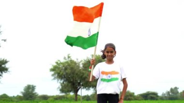 Elinde Kızılderili bayrağı tutan ve gülümseyen sevimli bir Hintli kız. Hindistan 'da Bağımsızlık Günü veya Cumhuriyet Günü' nü kutluyoruz. Tiranga 'nın gururunu gösteren bir kız. Har Ghar Tiranga