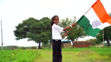 Elinde Kızılderili bayrağı tutan ve gülümseyen sevimli bir Hintli kız. Hindistan 'da Bağımsızlık Günü veya Cumhuriyet Günü' nü kutluyoruz. Tiranga 'nın gururunu gösteren bir kız. Har Ghar Tiranga