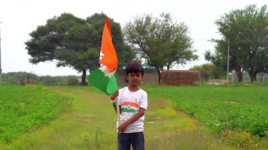Mutlu Hindistan Sevimli Gülümseyen küçük çocuk dışarıda parka üç renkli bayrak sallayarak Bağımsızlık Günü 'nü veya Cumhuriyet Günü' nü kutluyor..