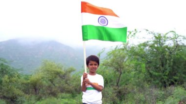 Beyaz ırktan yakışıklı küçük bir Hintli çocuk ya da çocuk Hindistan ulusal bayrağından ayakta duran ve vatanseverlik gösteren bir bebek giyer. Har Ghar Tiranga