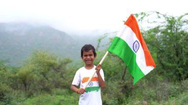Beyaz ırktan yakışıklı küçük bir Hintli çocuk ya da çocuk Hindistan ulusal bayrağından ayakta duran ve vatanseverlik gösteren bir bebek giyer. Har Ghar Tiranga