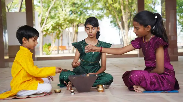 Geleneksel kıyafetli bir Hintli aile, evlerinde enerjilerini dengelemek için bir rahip tarafından yönetilen Yagya veya Havan 'ı icra eder. Bu kutsal pooja uyum ve pozitif enerji içindir..