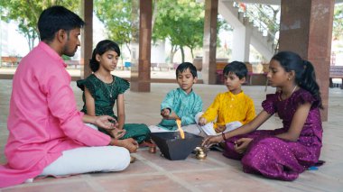 Geleneksel kıyafetli bir Hintli aile, evlerinde enerjilerini dengelemek için bir rahip tarafından yönetilen Yagya veya Havan 'ı icra eder. Bu kutsal pooja uyum ve pozitif enerji içindir..