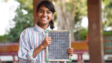 Happy Indian school girl child standing  in front of black chalkboard background. Education Concept or Back to School clipart