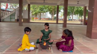 Geleneksel kıyafetli bir Hintli aile, evlerinde enerjilerini dengelemek için bir rahip tarafından yönetilen Yagya veya Havan 'ı icra eder. Bu kutsal pooja uyum ve pozitif enerji içindir..
