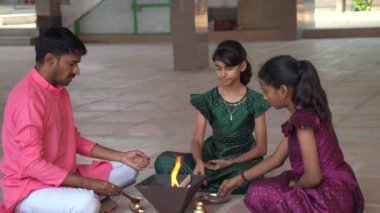 Geleneksel kıyafetli bir Hintli aile, evlerinde enerjilerini dengelemek için bir rahip tarafından yönetilen Yagya veya Havan 'ı icra eder. Bu kutsal pooja uyum ve pozitif enerji içindir..