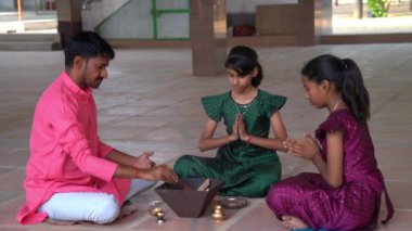 Geleneksel kıyafetli bir Hintli aile, evlerinde enerjilerini dengelemek için bir rahip tarafından yönetilen Yagya veya Havan 'ı icra eder. Bu kutsal pooja uyum ve pozitif enerji içindir..