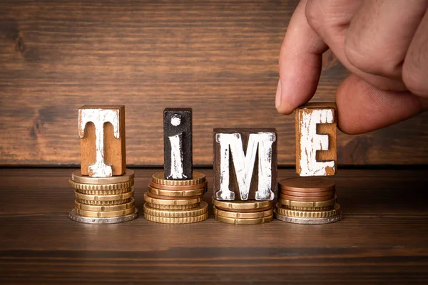 TIME. Text and change in pile on wood texture background.