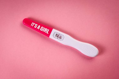 O bir kız. Pembe arka planda pozitif hamilelik testi.