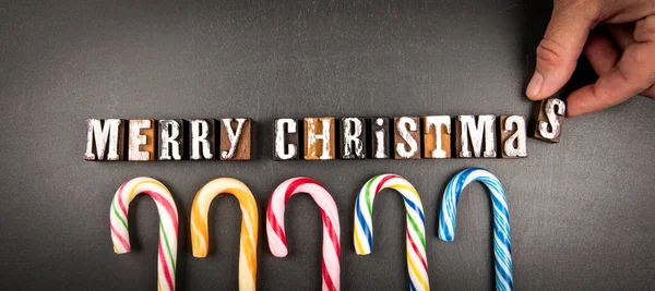 メリークリスマス 暗い黒板の背景に木製のアルファベットとキャンディーの缶 — ストック写真