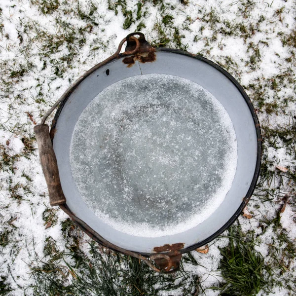 Frozen water, ice in a metal bucket. Weather and winter.
