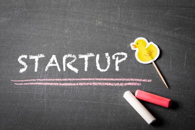 Başlangıç konsepti. Kara bir karatahtanın üzerindeki yazı ve renkli tebeşir parçaları.