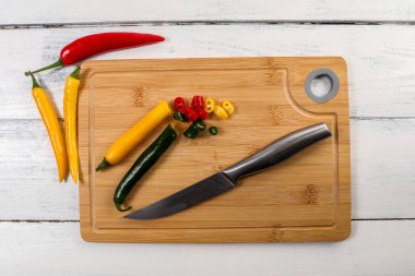Red, green and yellow peppers on a bamboo cutting board.