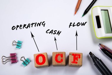 OCF - Operating Cash Flow. Wooden blocks on a white office table.
