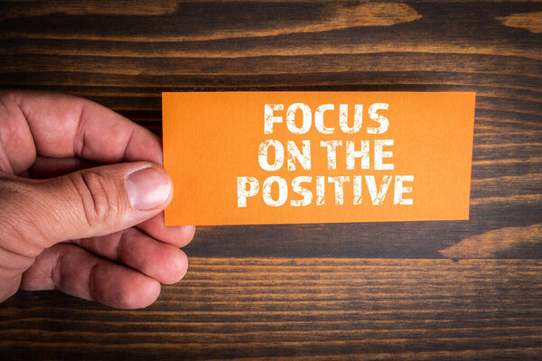 Focus on the Positive. Piece of paper with a text in a mans hand.