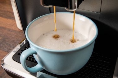 Making coffee in a blue cup, using a coffee machine.
