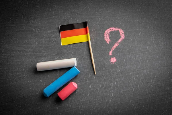 Germany flag and question mark on a chalk board. Politics and economics concept.