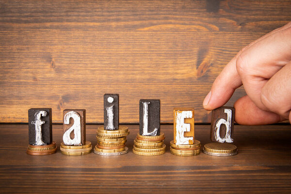 FAILED. Business concept. Alphabet blocks and change on wood texture background.