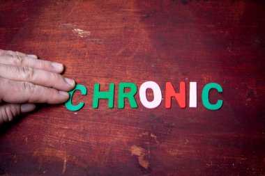 KRONİK. Sağlık kavramı. Ahşap doku arkaplanı üzerine renkli metin.