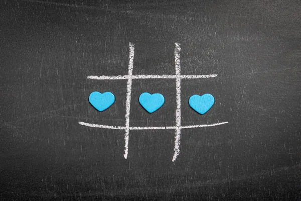 Blue hearts on the chalk board. Game of tic tac.