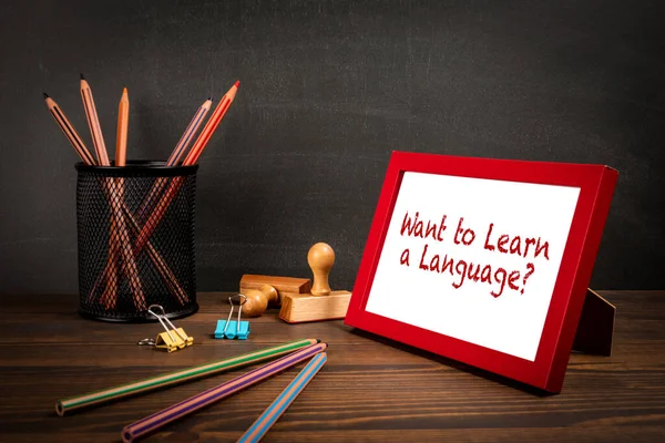 Want to Learn a Language. Picture frame with text on wooden table.