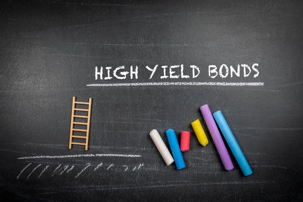 High yield bonds. Text and colored pieces of chalk on a dark board.