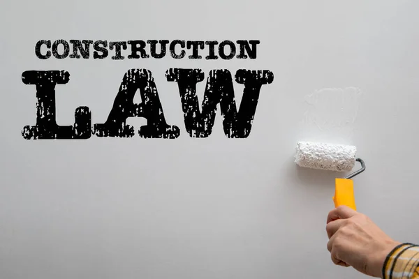 Construction law concept. Worker paints a white wall.