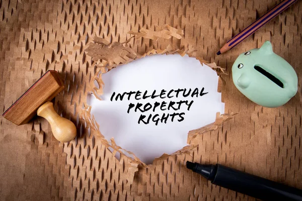 INTELLECTUAL PROPERTY RIGHTS. Piggy bank and black marker on cardboard background.