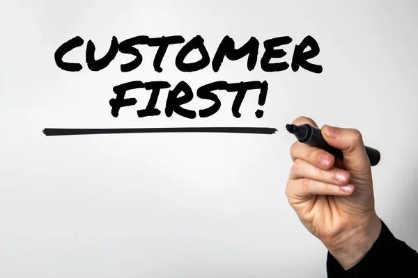 Customer First. Hand with marker writes text.