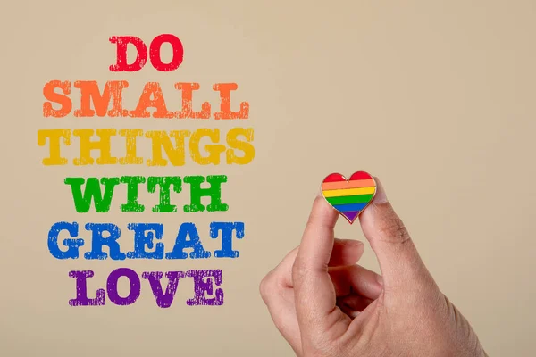 Do Small Things With Great Love. Rainbow colored heart and text on a light background.