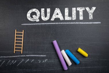 Nitelik kavramı. Metin, minyatür merdivenler ve koyu renkli tebeşir parçaları..