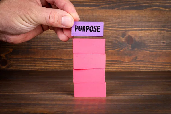 Purpose Concept. Purple and red blocks in a pile on a wooden texture background.