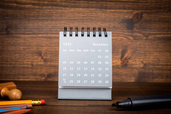2023 December. Black paper calendar on a wooden table. Time planning, day counting and holidays.