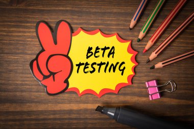 Beta Testi. Ahşap doku arkaplanı üzerine metin içeren yapışkan bir not.