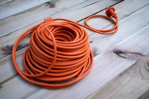 Pomarańczowy Kabel Elektryczny Przedłużacz Zwinięty Drewnianym Stole — Zdjęcie stockowe