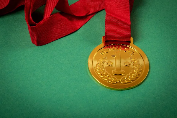 Gold medal with a red ribbon on a green background. Copy space. Close up.