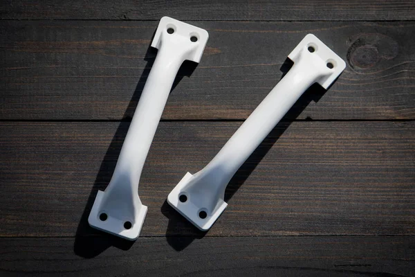 stock image White plastic door handles for a farm building on a wooden texture background. View from the top.