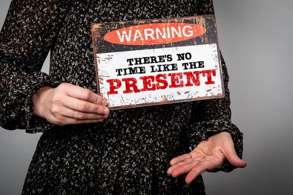 Theres No Time Like the Present. Warning sign in womans hands.