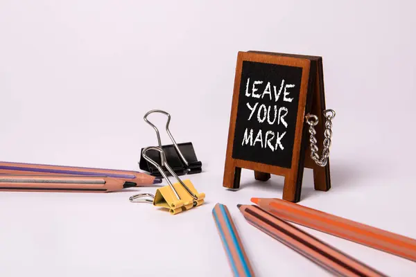 Leave Your Mark. Miniature chalkboard with text on a white office table.
