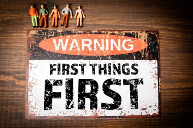 First things first. Warning sign with text on wood texture background. clipart