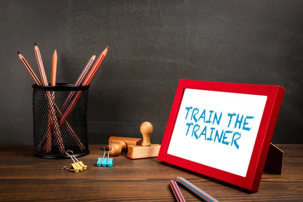 Train The Trainer. A picture frame on a wooden office table.